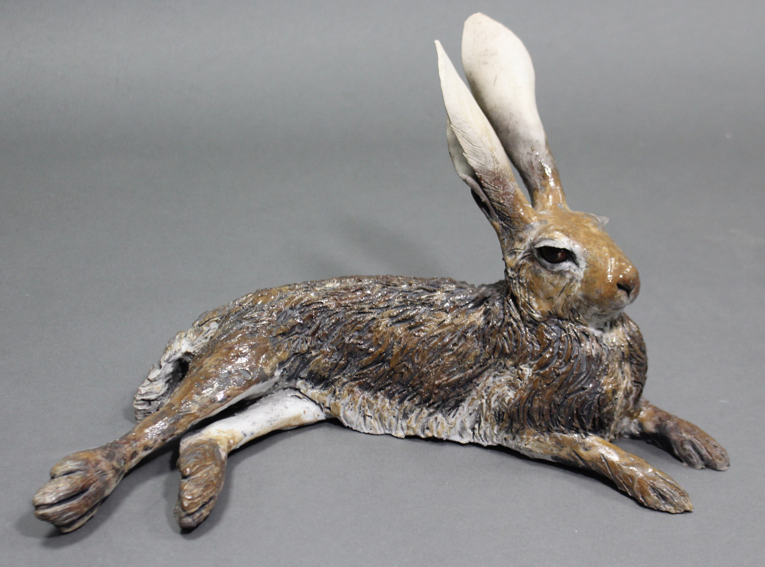 NICK MACKMAN; a contemporary ceramic sculpture titled: “Lying Down Hare”, glazed in naturalistic