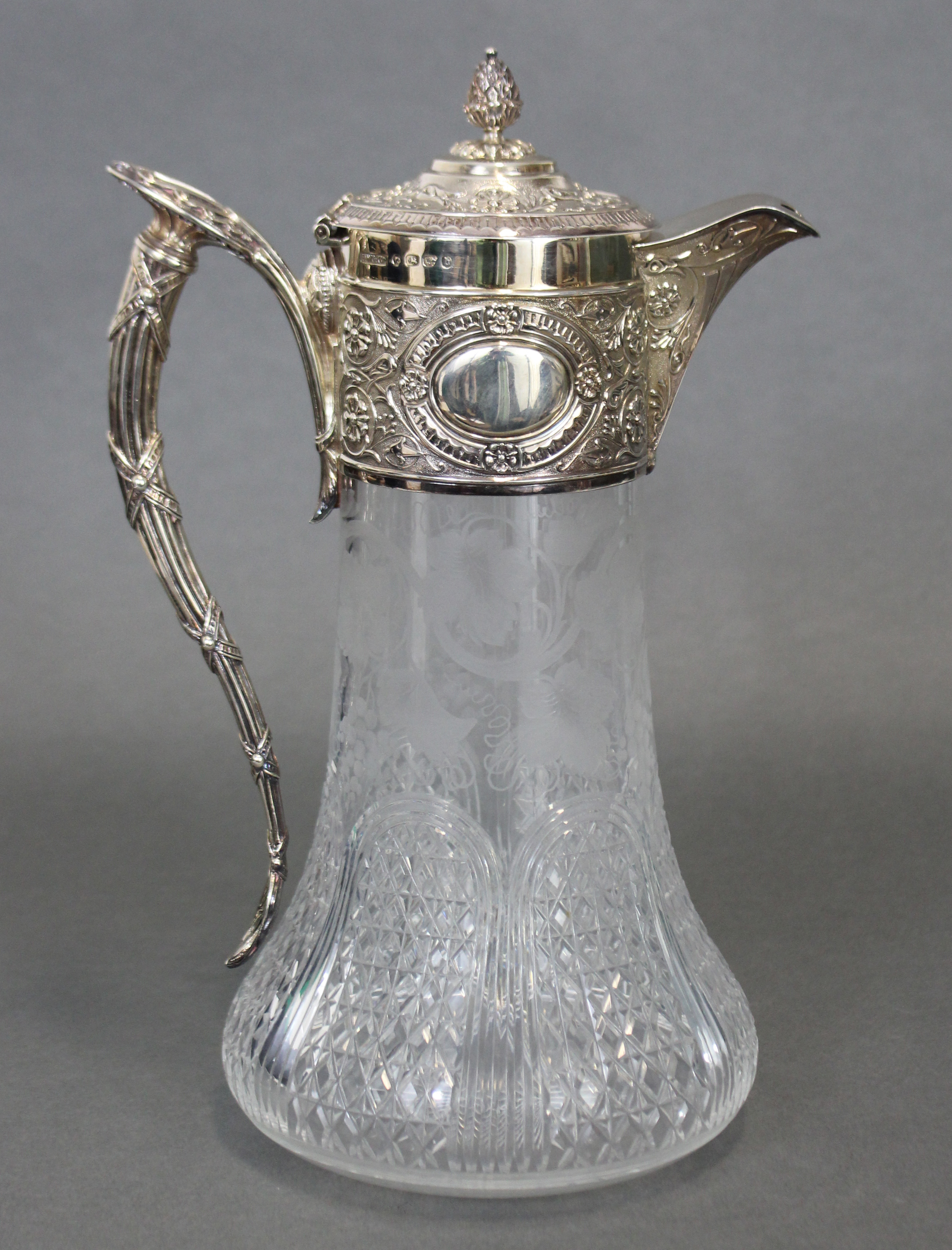 A VICTORIAN SILVER-MOUNTED CLARET JUG, the broad silver neck-mount, hinged lid, & enclosed spout