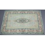A Kashmiri wool chain rug of pale green ground with a central cartouche surrounded by floral motifs,