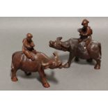 A pair of Chinese carved hardwood models of figures riding buffalo, each 6” long by 5½” high.