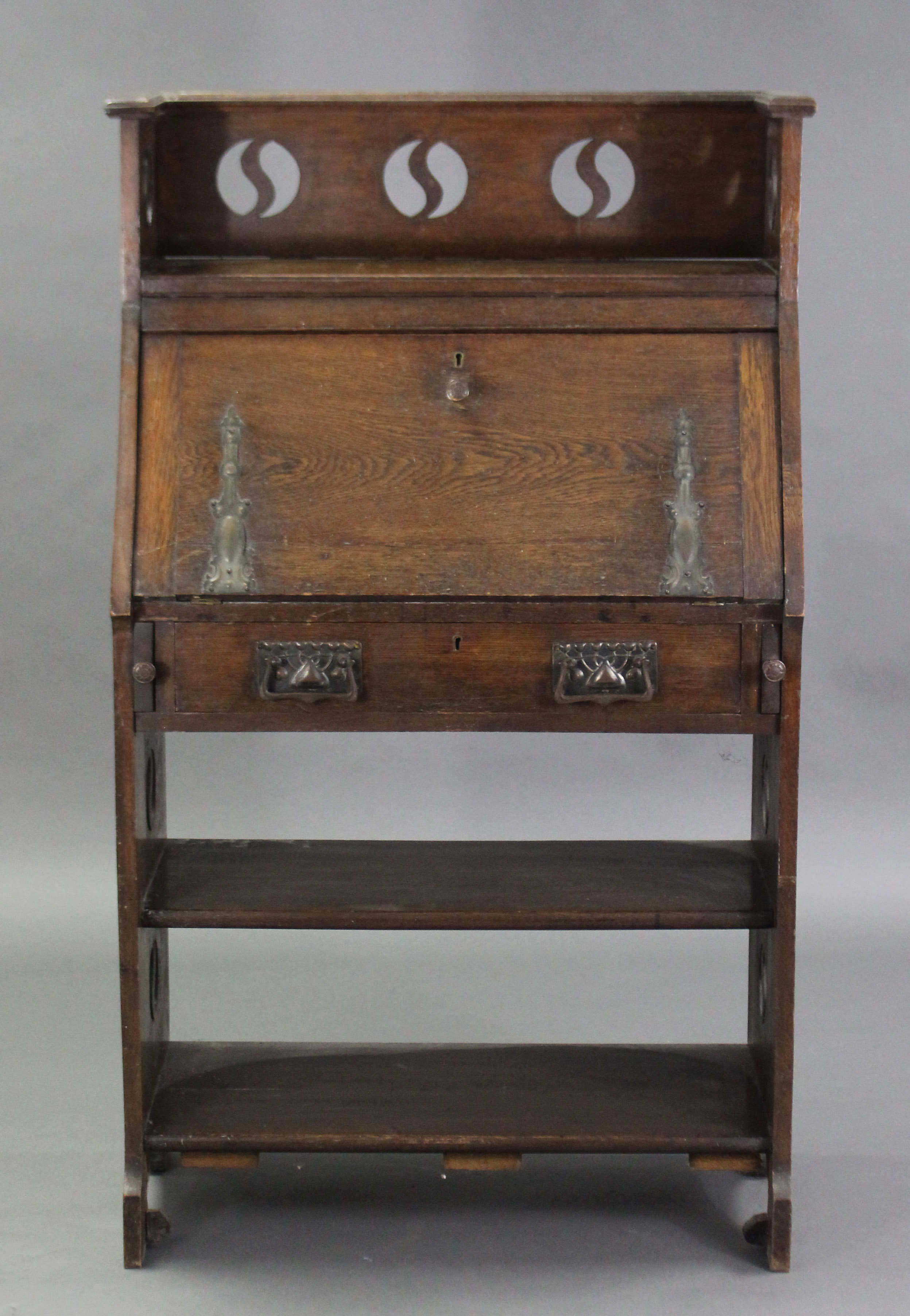 An Arts & Crafts oak upright hall cabinet, with pierced roundels to the tray top & sides, a