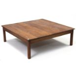 A large teak low square coffee table on four short square legs, 47¾” wide.