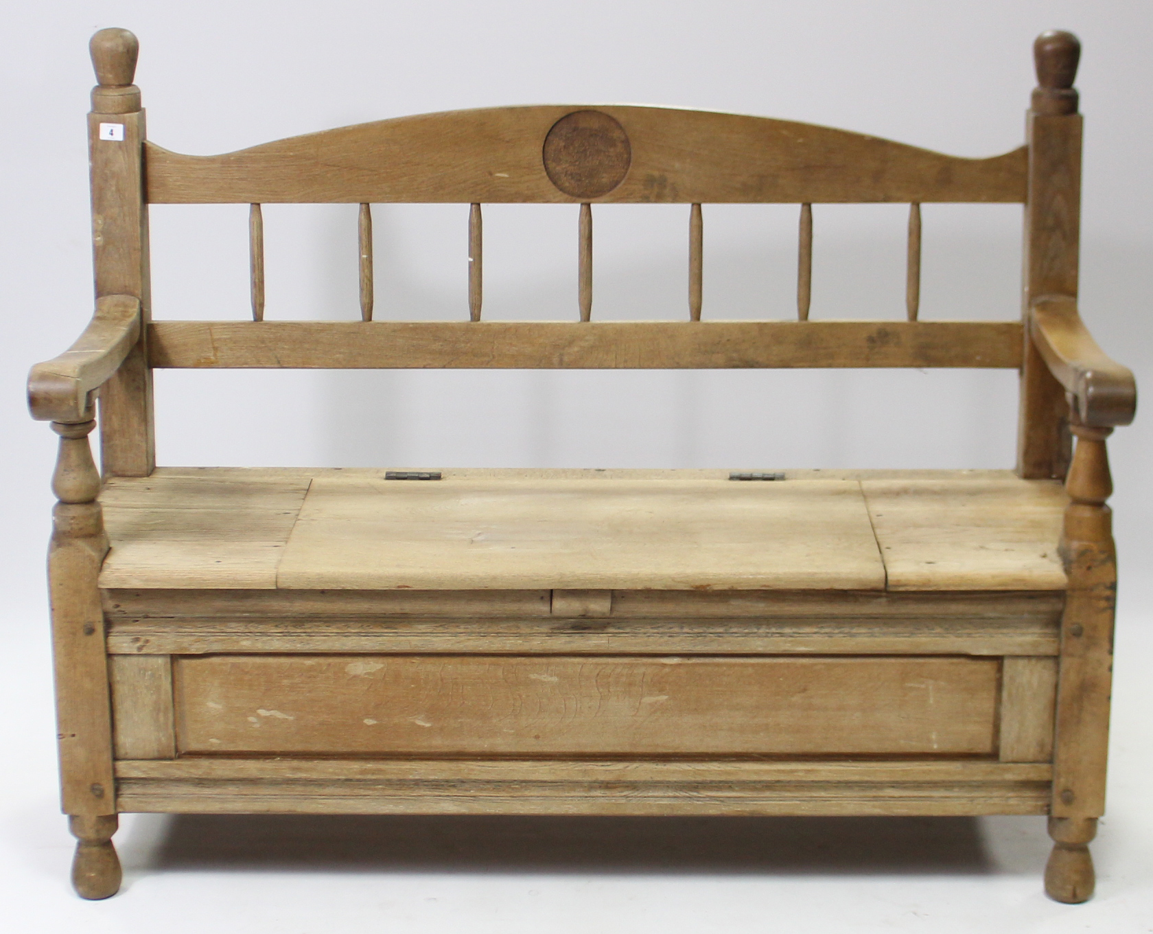 A light oak hall bench with spindle-rail to the back, with hinged lift-seat, panelled front & sides,