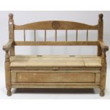 A light oak hall bench with spindle-rail to the back, with hinged lift-seat, panelled front & sides,