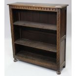 A carved oak standing open bookcase with two adjustable shelves, & on bun feet, 41¾” wide x 45½”