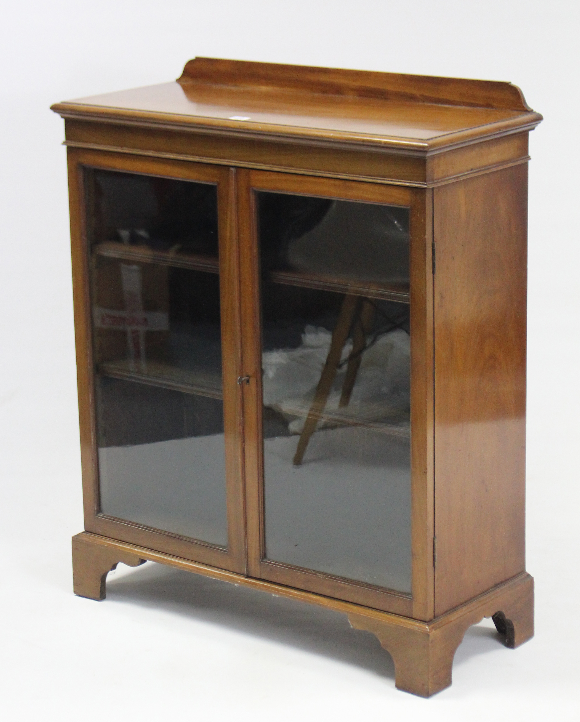 A mahogany dwarf cabinet, with two adjustable shelves enclosed by pair of glazed doors, & on bracket