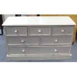 A white painted pine low chest fitted with an arrangement of six drawers with turned knob handles, &