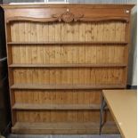 A pine tall standing five-tier open bookcase with carved frieze, & on plinth base, 72” long x 75½”