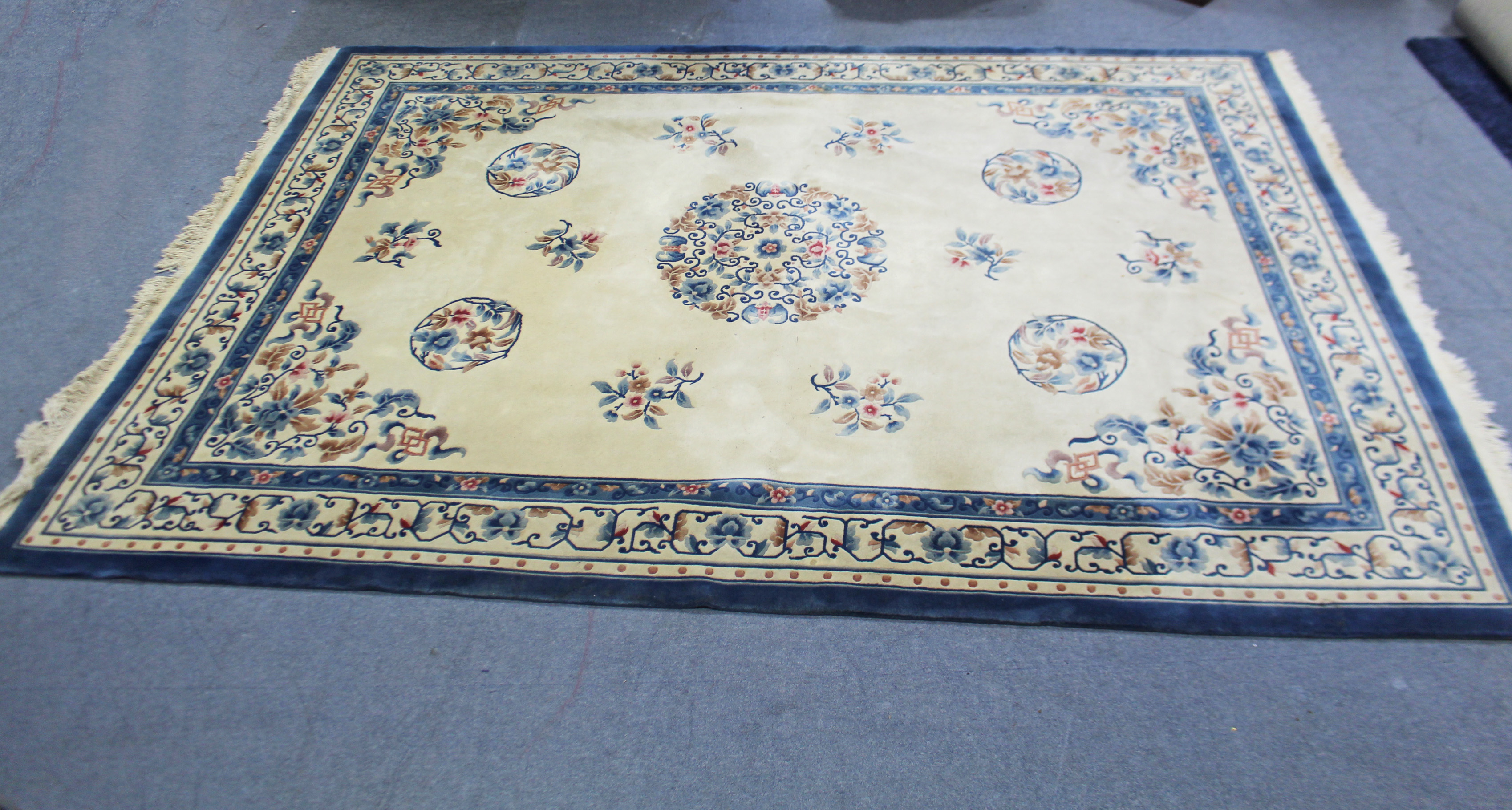 A Chinese-style carpet of cream ground & with bright-coloured floral design to centre within a