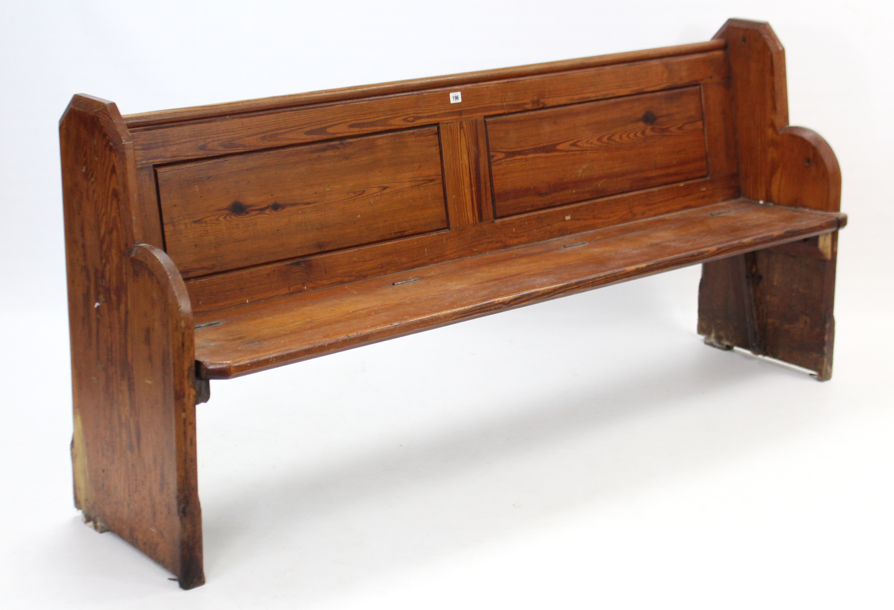 A Victorian pitch-pine pew with panelled back, hinged seat, & on shaped end supports, 74” long x 35”