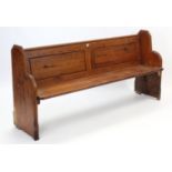 A Victorian pitch-pine pew with panelled back, hinged seat, & on shaped end supports, 74” long x 35”