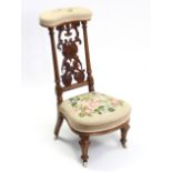 A Victorian walnut prie-dieu chair with pierced & carved panel back, floral embroidered padded seat,