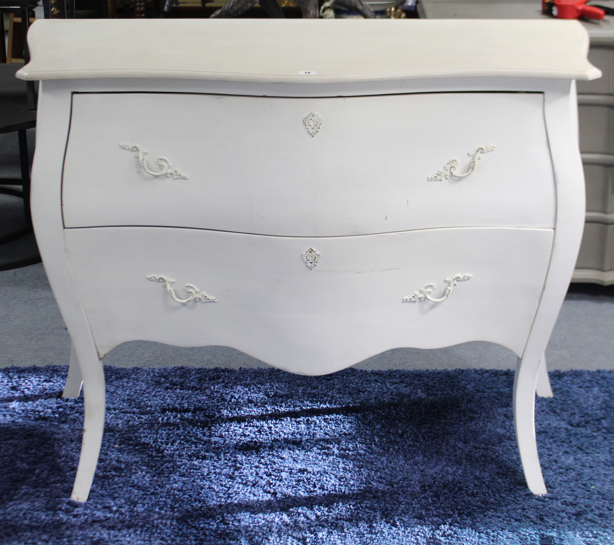 A continental-style white painted wooden “bombe” chest fitted two long drawers with cast-iron