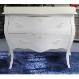 A continental-style white painted wooden “bombe” chest fitted two long drawers with cast-iron