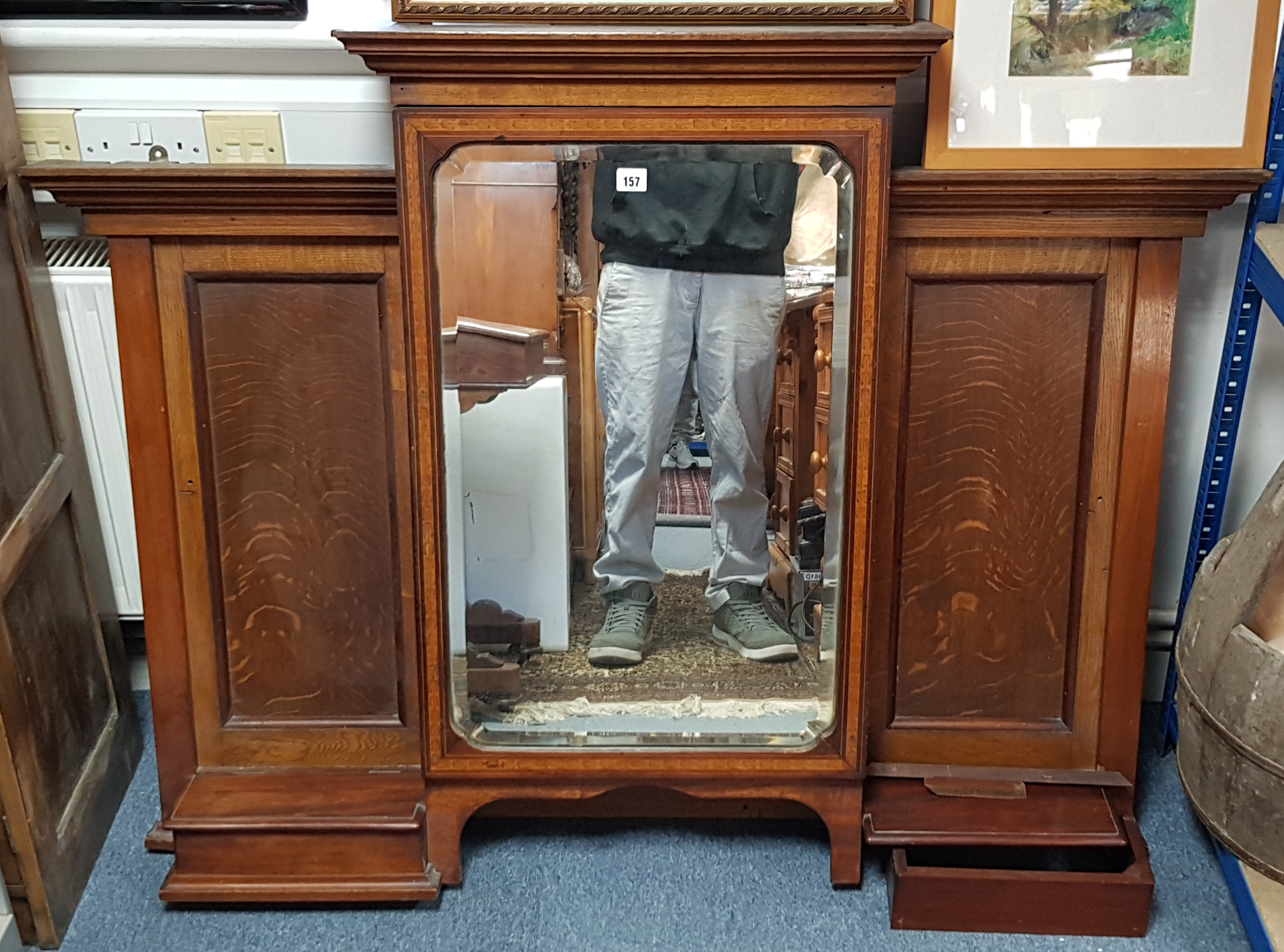 An early 20th century inlaid oak overmantel with cabinet to centre enclosed by bevelled mirror door,