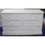A white painted pine low chest fitted with an arrangement of six drawers with turned knob handles, &