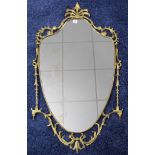 A brass-frame large shield-shaped wall mirror with pierced scroll border, 43” x 24”; together with
