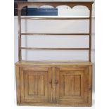A late 19th/early 20th century pine kitchen dresser the upper part fitted three open shelves, the