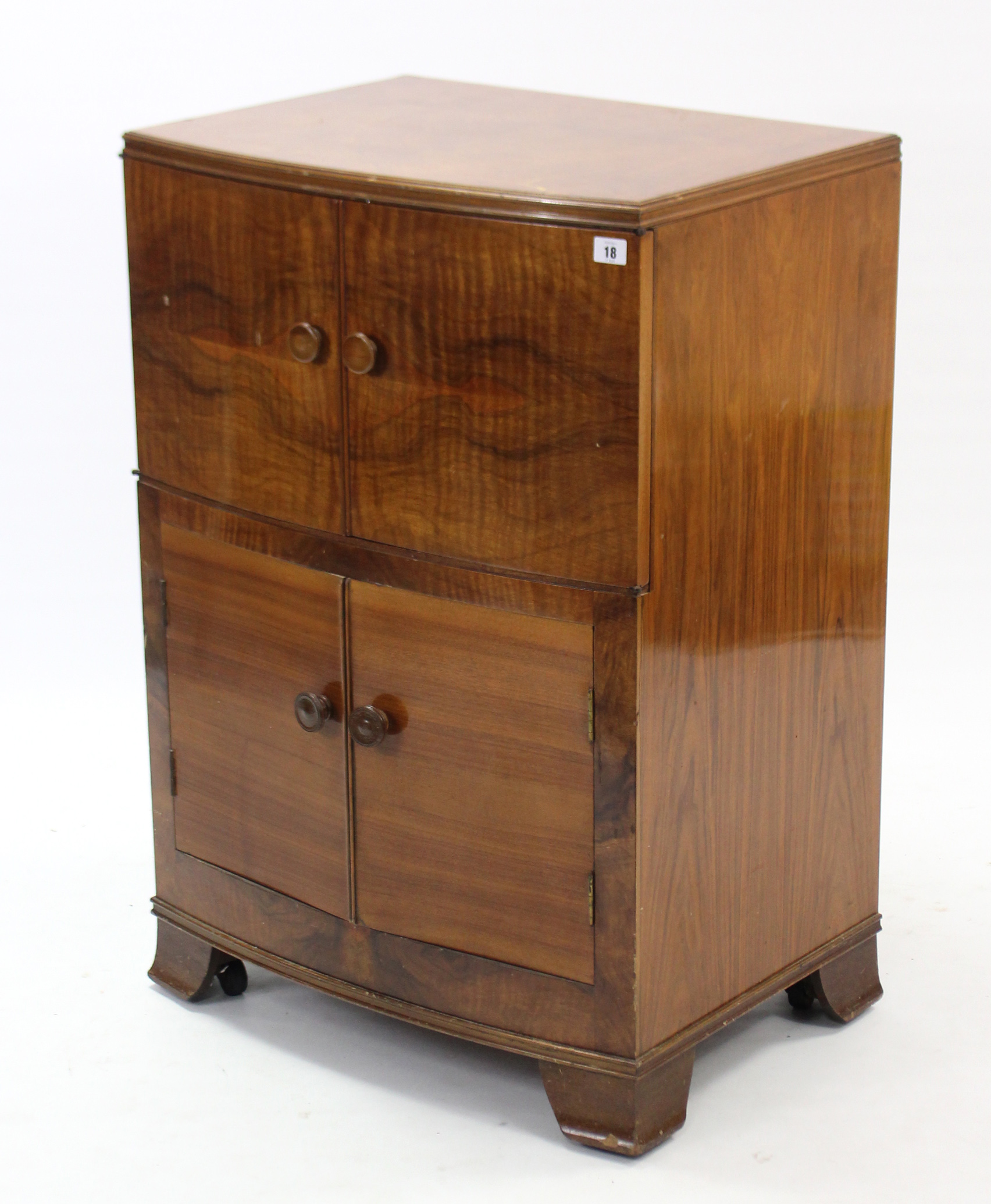 A mid-20th century walnut bow-front cabinet, enclosed by two pairs of panel doors & on bracket feet,