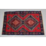 A Baluchi rug of dark blue, red & ivory ground with two central lozenges within a narrow border;