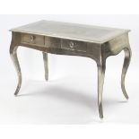 A continental-style silvered-finish writing table fitted two frieze drawers, & on slender cabriole