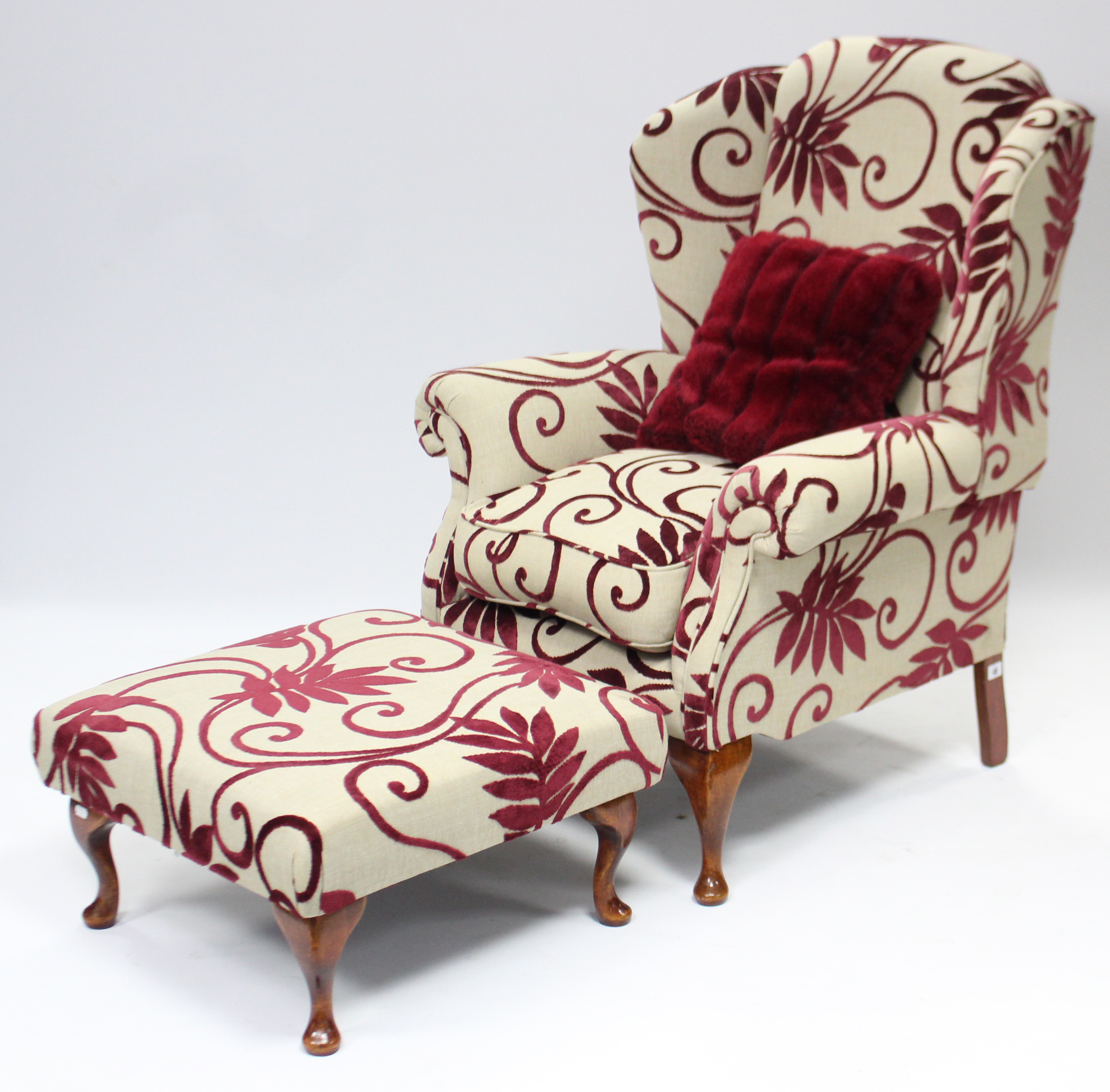 A wing-back armchair upholstered fawn & crimson foliate material, & on short cabriole legs & pad