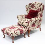 A wing-back armchair upholstered fawn & crimson foliate material, & on short cabriole legs & pad