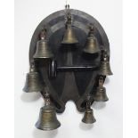 A SET OF EIGHT ANTIQUE BRONZED TUNING BELLS mounted on an ebonised horse-shoe shaped plaque with