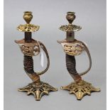 A pair of cast-metal novelty candlesticks each in the form of a German military sword handle, 10¾”