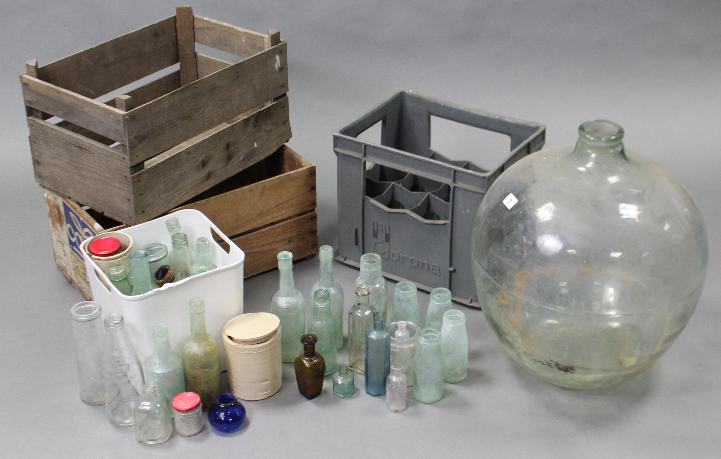 A Corona grey plastic twelve division crate; together with two wooden crates; a glass carboy; &