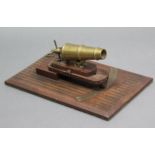 A MINIATURE BRASS DESK CANON ORNAMENT inscribed: “W. NORTH 1848”, 7” long & mounted on an oak