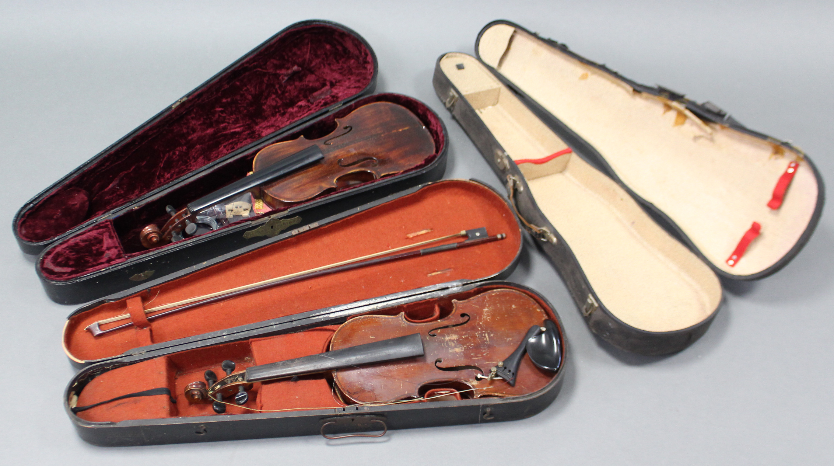 Two violins; a violin bow; & three violin cases.