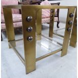 A Kelly Wearstler brass effect two tier lamp table with inset glazed panels and ball ornament,