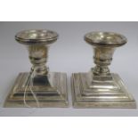 A pair of loaded silver dwarf candlesticks with vase shaped sockets, on stepped,
