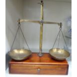 Early 20thC lacquered brass beam balance scales, the twin pans on chains, operated by a treadle arm,