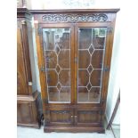 An Old Charm stained and carved oak cabinet bookcase, enclosed by a pair of three-quarters height,