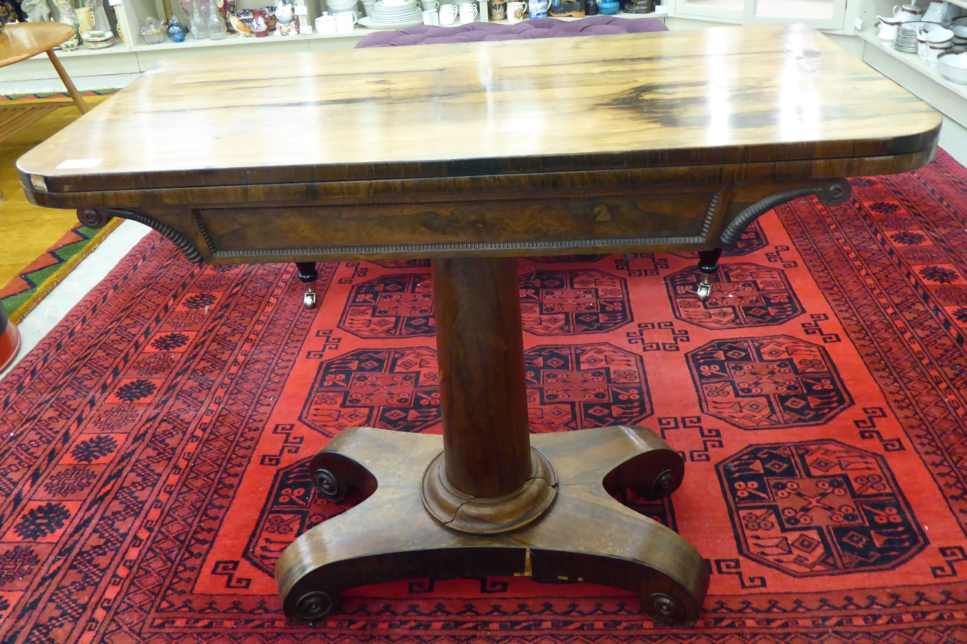 A Regency rosewood card table with a foldover top, enclosing a baize lined interior,