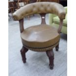 A late Victorian/Edwardian mahogany framed library chair with a round, open back, on swept uprights,