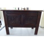An early 20thC profusely carved oak coffer of small proportions with a twin panelled front and