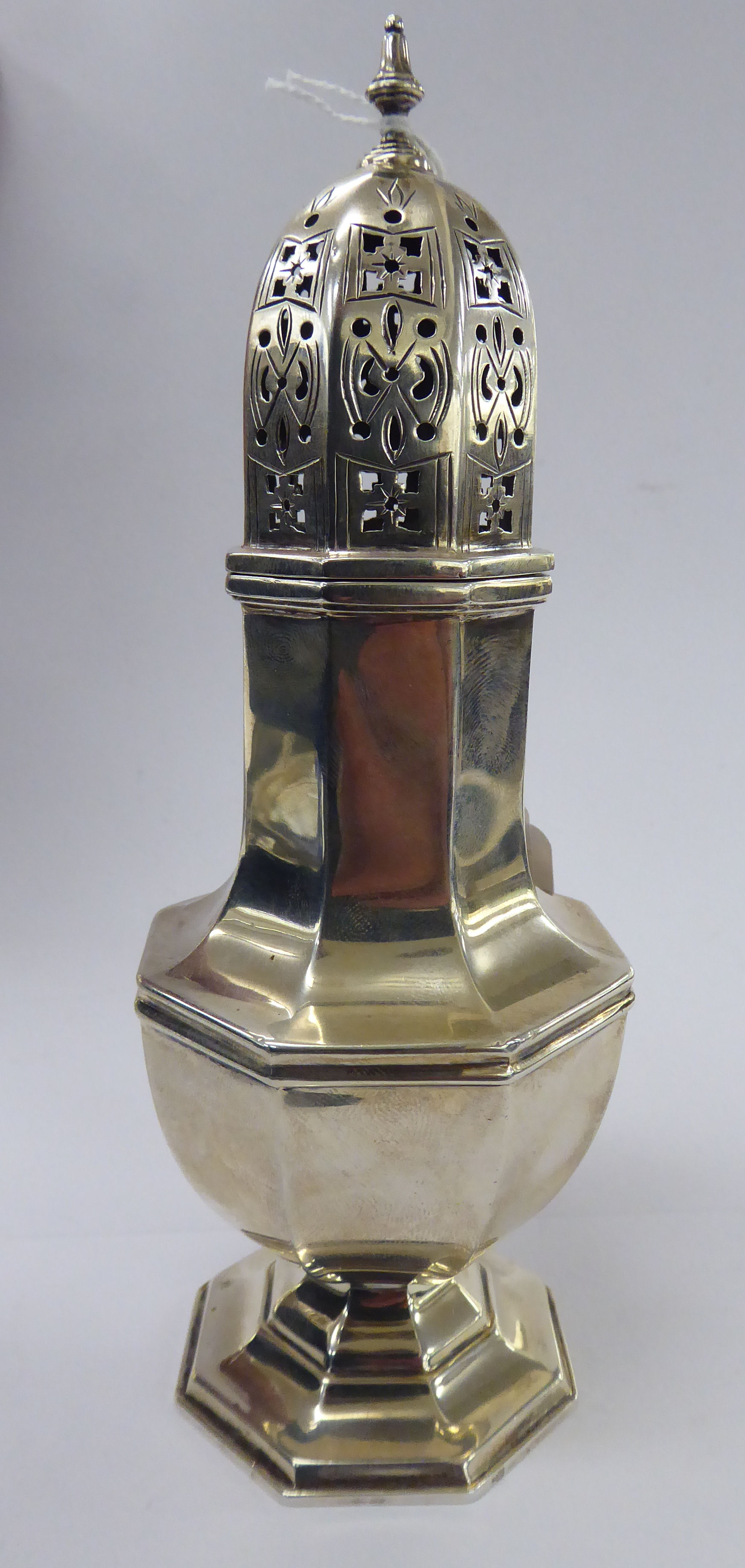 A silver caster of octagonal pedestal vase design with a decoratively pierced domed cover and