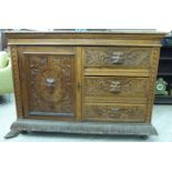 A late Victorian profusely carved light oak sideboard with figural mask handles and foliate