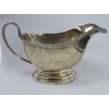 A late Victorian silver sauce boat with a gadrooned rim and loop handle,