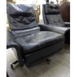 A 1960s/70s recliner chair with a square back low, level enclosed arms and a retractable footrest,