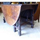 A 1920s stained oak dropleaf dining table, the oval top raised on a ring turned,