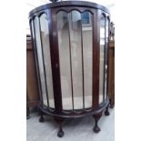 A 1930s mahogany demi-lune fully, glazed front display cabinet, enclosed by a central door,