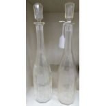 A pair of late 19thC clear, faceted and tapered glass wine decanters and stoppers,