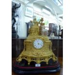 A late 19thC French elaborately cast gilt metal cased mantel clock, featuring a standing woman,