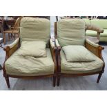 A pair of Wesley Barrell walnut framed bergere style enclosed armchairs with low arched backs and
