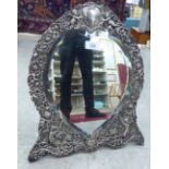 A late Victorian silver mounted dressing table mirror, embossed with swags, cherubic figures,