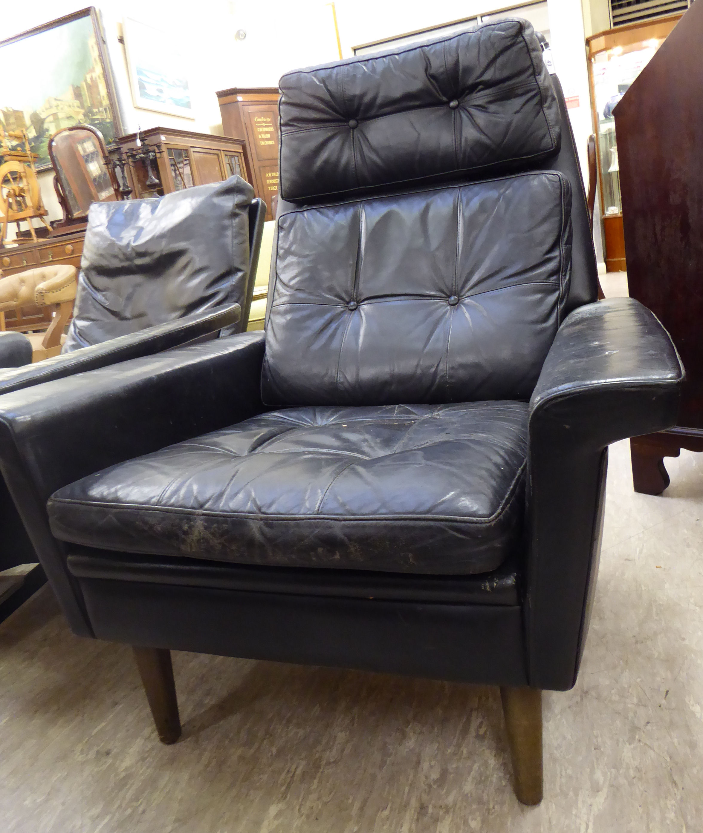 A 1960s/70s chair with a high back and low, level enclosed arms, upholstered in buttoned,